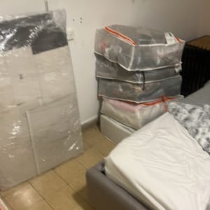 אריזות פלסטיק עם בגדים ליד מיטה