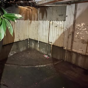 פינה חיצונית עם גדר עץ, צינורות ומיכל צבע על הקרקע