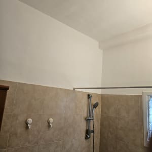 קיר צבוע בלבן מעל אריחי קרמיקה במקלחת