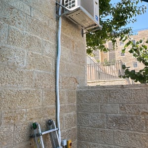 יחידת מיזוג אוויר מותקנת על קיר עם סולם מתחתיה
