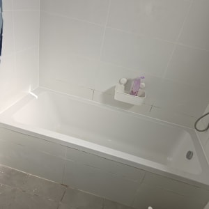 אמבטיה לבנה עם קיר אריחים לבנים