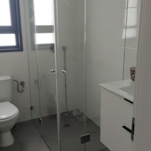 מקלחון זכוכית פינתי מותקן בחדר רחצה מודרני