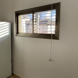 חלון עם תריסים פתוחים וקיר נקי