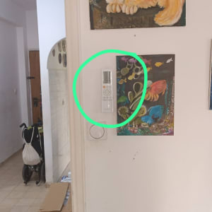 שלט רחוק למזגן תלוי על הקיר ליד ציורים