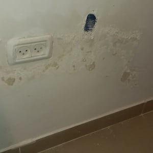 קיר עם סימני רטיבות ושקע חשמלי כפול