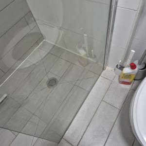 מקלחת עם רצפת אריחים וכלי ניקוי