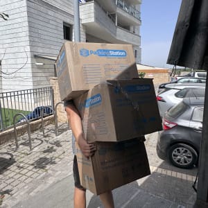 אדם נושא שלוש קופסאות קרטון גדולות ברחוב