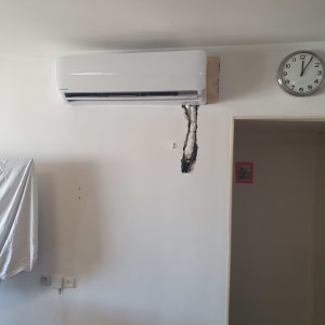 מזגן מותקן על קיר עם חיבורים חשופים