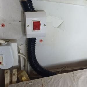 מתג חשמלי עם כבל גמיש שחור על קיר לבן