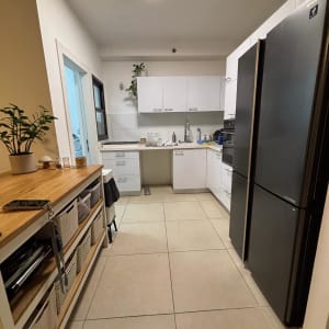 מטבח מאורגן עם ארונות לבנים ומקרר שחור