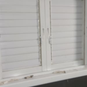 תריסים לבנים מותקנים על חלון קיר כהה