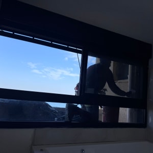 אדם מנקה חלון מבחוץ עם נוף לים