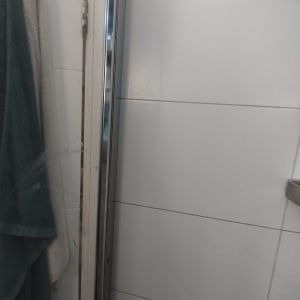 דלת מקלחת מזכוכית עם מגבות תלויות