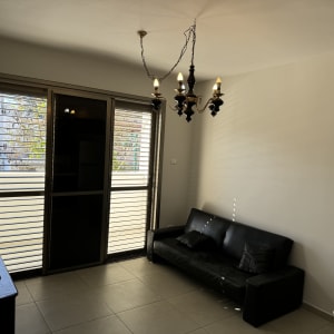 קיר צבוע בלבן עם ספה שחורה לידו