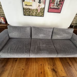 ספה אפורה עם כתמים על רצפת עץ