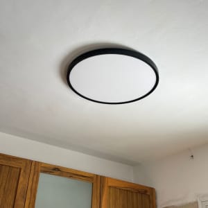 מנורה עגולה מותקנת על תקרה מעל ארונות עץ במטבח