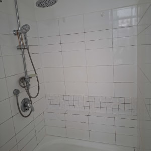 חדר אמבטיה עם מקלחת ואריחים לבנים