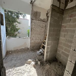 אתר שיפוצים עם קירות בלוקים, סולם וחוט חשמל