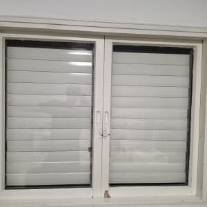 חלון עם תריסים סגורים במסגרת לבנה