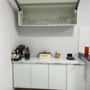 ארון מטבח פתוח עם כוסות יין, בקבוקי שתייה וקופסת לחם