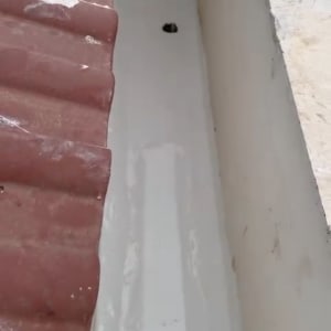 גג אטום עם חומר איטום לבן ליד רעפים אדומים