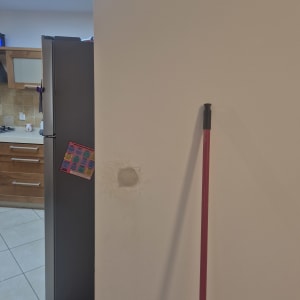 מטבח עם מקרר ומטאטא ליד קיר