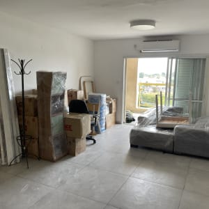 חדר עם קרטונים, רהיטים עטופים בניילון, כיסא ושולחן הפוך