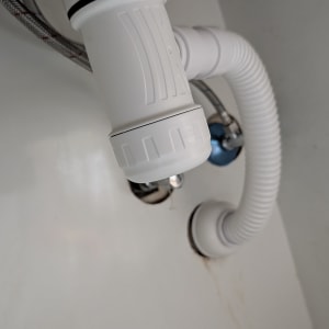 צינור פלסטיק לבן מתחת לכיור עם חיבורים