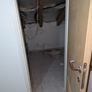 חדר קטן עם תקרה פתוחה וחוטי חשמל גלויים