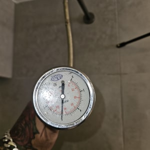 מד לחץ מים מוחזק ביד, צינור מים ברקע