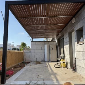 פרגולת אלומיניום שחורה עם שלבים דמוי עץ ותאורת לד בחצר בית