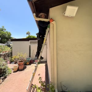 אדם על סולם מתקין מרזב על גג בית