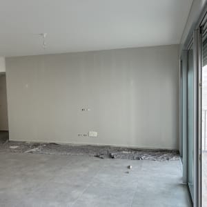 קיר צבוע בלבן עם סולם וציוד צביעה