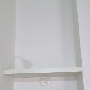 מדף עץ לבן מותקן על קיר לבן