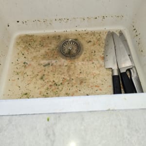 כיור מלא מים מלוכלכים עם סכינים בצד