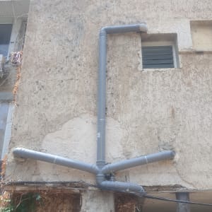 צינורות פלסטיק אפורים מותקנים על קיר חיצוני