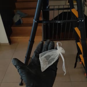 יד עם כפפה מחזיקה שקית עם חומר ליד סולם
