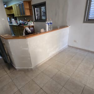 קיר צבוע עם מטבח ברקע ובקבוקי מים על הדלפק