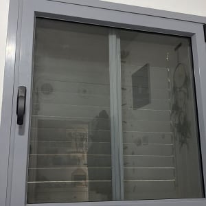 חלון עם תריסים אפורים על קיר לבן