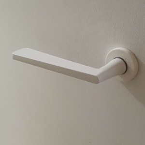 ידית דלת לבנה על רקע קיר