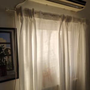 מזגן תלוי על קיר מעל וילון לבן