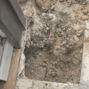 חפירה באדמה עם צינור חשוף ליד קיר