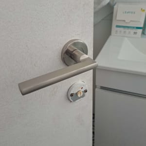 ידית דלת מתכתית על דלת לבנה בחדר אמבטיה