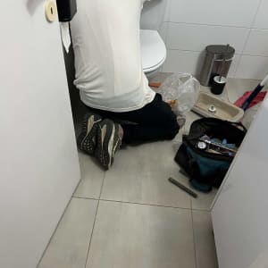 אדם עובד על תיקון אסלה בחדר אמבטיה עם כלים