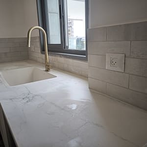 שיש חדש עם כיור וברז זהב במטבח משופץ