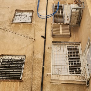 צנרת חיצונית על קיר בניין עם חלונות וסורגים