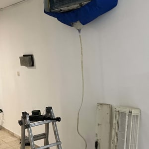 מזגן מפורק עם כיסוי כחול וסולם לידו