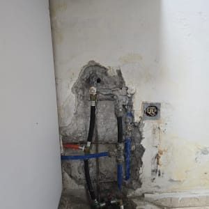 צינורות מים חשופים בקיר עם סימני רטיבות