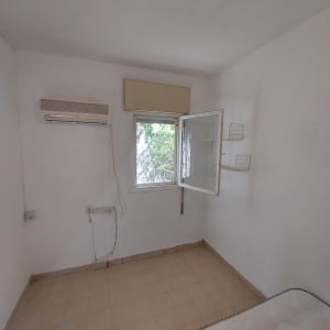 חדר עם מזגן מותקן על הקיר וחלון פתוח