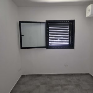 חדר ריק עם חלון פתוח ורצפת אריחים אפורה